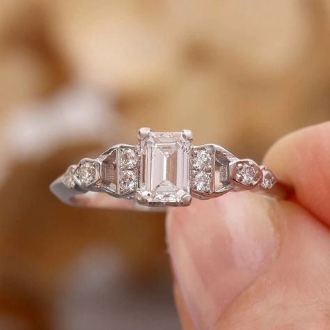 An Elegant Mid-Century Emerald Cut Diamond Engagement Ring💎 A gorgeous Emerald Cut diamond weighing 0.54 cts and assessed in the setting as G color and SI2 clarity is set between "half-hitch" styled shoulders set with eight round brilliant cut diamonds (total diamond weight 0.11 cts, GH color and VS-SI clarity. This beautiful vintage ring is a size 6.5 full and may be resized, please inquire. American made in Platinum. #leighjayandco #artdecoengagementring #vintageengagementring #artdeco... Emerald Cut Diamond Engagement Ring, Beautiful Rings Vintage, Emerald Cut Diamond Engagement, Emerald Cut Diamond, Art Deco Engagement Ring, Emerald Cut Diamonds, Vintage Ring, Round Brilliant Cut Diamond, Vintage Engagement Rings