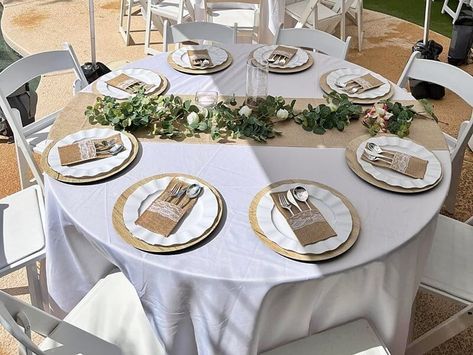 Give your outdoor party tables a bucolic look by using white tablecloths topped with faux burlap table runners. Arrange faux wood charger plates, wavy rimmed white plates, & burlap/lace single set silverware holders to add a chic country charm to your tablescape. For added radiance and colorful beauty, swathe a eucalyptus leaf & ivory rose flower garland vine on your tables together with clear cylinder glass vases filled with LED string lights for an instant magical flair. Gold Charger Plates Wedding Wood Table, Birch Charger Plates, Rustic Plate Charger, Rustic Outdoor Table, Wood Charger Plates, Burlap Table Runner With Wood Centerpiece, Burlap Lace Wedding Table, Rose Flower Garland, Wood Plate Chargers