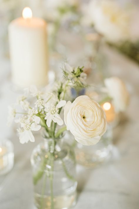 This all white wedding color scheme was so dreamy with the blurred candles behind and the bud vases. White Flowers In Small Vases, Bud Vases Cocktail Hour, Bud Vase With White Flowers, Bud Vase Centerpiece Round Table Wedding, Bud Vases Circle Table Wedding, Bud Vase And Candle Tablescape, Modern Bud Vases Wedding, White Flower Bud Vases Wedding, Circle Table Bud Vases