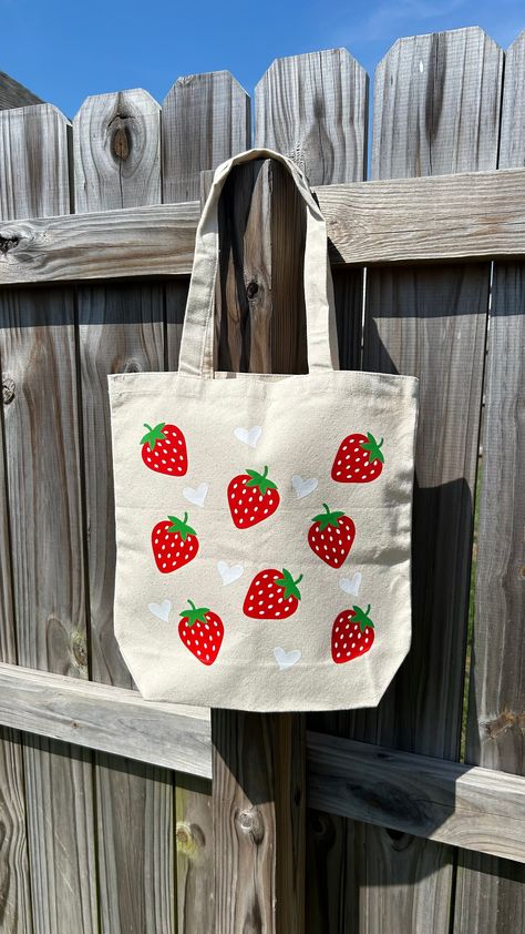 "Our Strawberry Hearts tote is the berry cutest on-the-go bag for you! This canvas tote is perfect for grocery runs, quick errands and more! Canvas tote with \"Strawberry Hearts\" design on one side.  This tote bag is the sweetest gift or prefect for yourself! Check out our matching strawberry keychain too!" Fruit Tote Bag Painting, Side Bag Aesthetic, Tote Bag Ideas Design, Canvas Tote Bag Painting, Tote Bag Painting Ideas Easy, Tote Bag Painting Ideas Aesthetic, Easy Tote Bag Painting, Canvas Bag Painting Ideas, Diy Tote Bag Painting Ideas