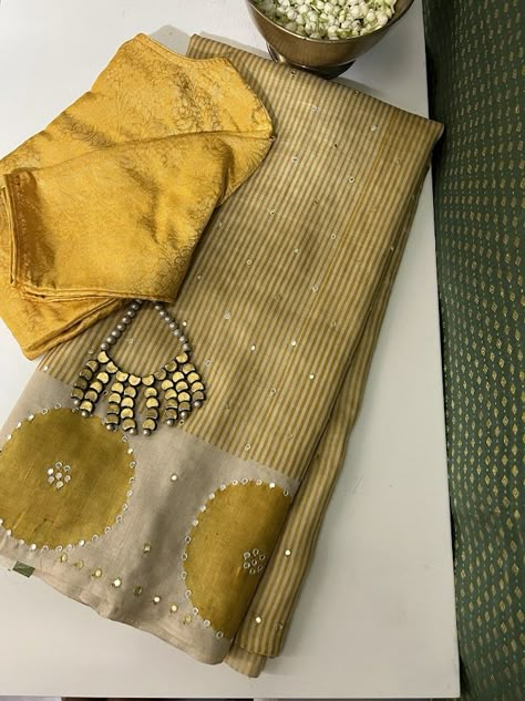 We are delighted to showcase distinctive designs in our Tashi collection, presenting a contemporary twist on Tussar sarees. Explore our exclusive creation featuring yellow stripes on beige handloom Tussar, enhanced with block prints and mirror work embellishments. Elevate your ensemble by pairing it with a yellow silk blouse from our curated collection. Indian Handloom Sarees, Cream Color Saree With Contrast Blouse, New Trend Blouse Designs, Cotton Silk Saree With Mirror Work, Festive Cotton Silk Saree With Mirror Work, Designer Sarees, Semi-stitched Cotton Silk Saree With Mirror Work, Striped Blouse Designs, Brown Tussar Silk Saree With Pallu Detail