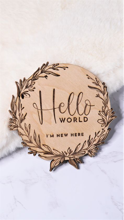 An 11cm wide, round, light brown, baby announcement wooden plaque that says "Hello world, I'm new here". The Hello is written in a script font and is large in the centre. The rest of the words are smaller and written in block capitals. There is a gorgeous floral engraved design around the words. The shape around the edges mimics the shape of the floral. Hello World Baby Announcement, Baby Announcement Sign, Brother Photos, Earth Baby, Birth Announcement Sign, Announcement Sign, Baby Birth Announcement, Baby Arrival, Hello World