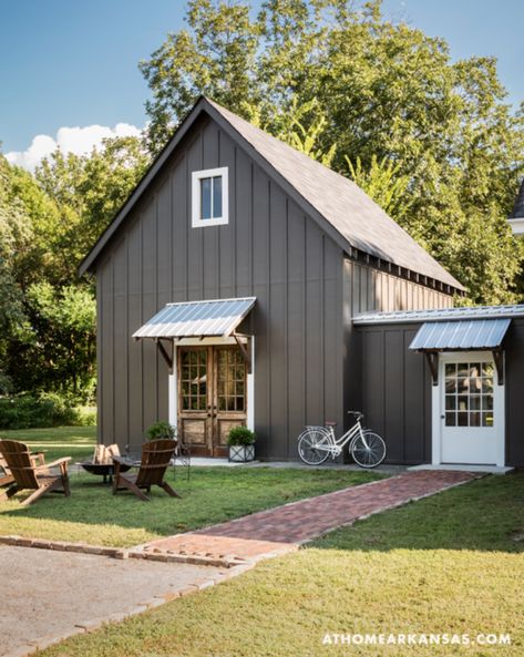 Gray-brown board and batten, white door/window trim, and stained wood accents, from At Home Arkansas. Metal Buildings With Living Quarters, Farmhouse Exterior Design, Metal Building Home, Board And Batten Siding, Young House Love, Unique Farmhouse, Casas Coloniales, Exterior Remodel, Metal Building Homes