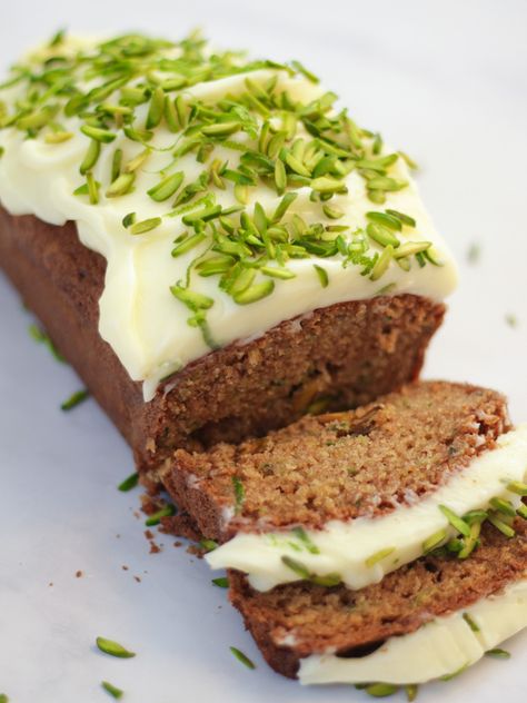 Side angle photo of baked courgette cake loaf topped with cream cheese icing and pistachio nut slices on white marble background. Courgette And Lime Cake, Courgette Cake Recipe, Courgette Cake, Pistachio Nut, Cake Recipes Easy, Cake Courgette, Vegetable Cake, Cake Loaf, Mascarpone Frosting