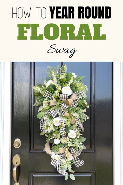 Tear drop shaped floral arrangement hanging on a black front door. Made of tons of faux greenery some leaf like and others and evergreen pine needle look.Think white flowers, tiny white flowers and white roses all placed around one large bow made of black and white check pattern, and white mesh ribbon and a brown ribbon with a black edge and white polka dots. Teardrop Swag Wreath, Making A Swag Wreath, How To Make A Teardrop Swag, Teardrop Swag Diy, Teardrop Wreaths For Front Door, Spring Door Swag, Diy Teardrop Wreath, Flower Swags Diy, How To Make A Swag Wreath