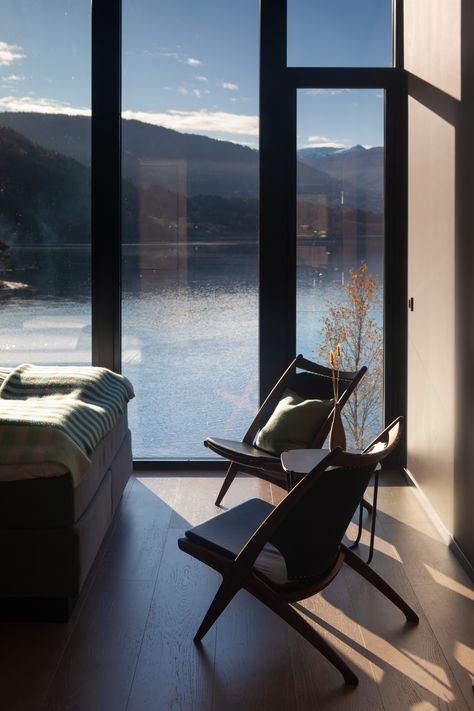 Hotel room with Norwegian design furniture and a glass fasade looking over the lakeside view towards the snow covered mountains in the background. Mountain Cabin Interior, Voss Norway, Lakeside Hotel, Norway Hotel, Norway Landscape, Cosy Fireplace, Mountain Hotel, Luxury Hotel Room, Forest Cabin