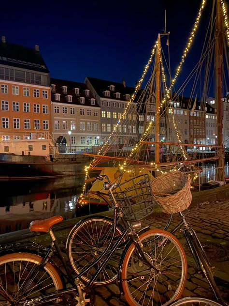 beautiful typical scenery of Copenhagen, pretty color houses in the side of a canal, surrounded by bikes and Christmas lights Copenhagen New Year, Copenhagen At Christmas, Fall In Copenhagen, Copenhagen New Years Eve, Living In Copenhagen, Copenhagen Fall Aesthetic, Copenhagen Christmas Aesthetic, Copenhagen At Night, Copenhagen Winter Aesthetic