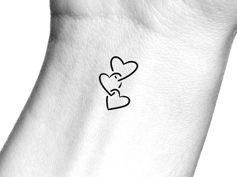 Hearts Temporary Tattoo Size: The size of this Temporary Tattoo is approximately 3/4 inch in length. If you would like this design in a smaller or larger size that isn't already listed, please message us directly on Etsy BEFORE placing your order so we can provide you with accurate pricing. Directions: 1.    Peel off the clear plastic layer with your fingernail or a pair of tweezers. Hold the temporary tattoo design side up in your hand and with your other hand run your thumb along the side of t Heart Within A Heart Tattoo, 3 Interlocking Hearts Tattoo, Heart Inside Heart Tattoo, Small Heart Tattoo On Hand, 4 Hearts Tattoo Family, Linked Hearts Tattoo, Tattoo Ideas Female Heart, Four Hearts Tattoo, Small Hearts Tattoo