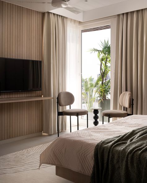 This guest bedroom exudes calm with light-toned finishes, featuring dyed oak wood veneer and beige textured laminate on wardrobes for added depth. The bed is designed to float above the floor, creating openness and maximizing space, while built-in shelves offer extra storage. Perforated shutters neatly conceal the AC unit, keeping the design sleek. A subtle green headboard adds a touch of color, complemented by custom bedside lights and built-in side tables. The paneled TV wall transitions in... Bed With Curtains Around It Wood, Oak Canopy Bed, Timber King Bed, Woodem Panel Wallpaper, Luxury Delicate Wood Bed, Tiered Ceiling, Green Headboard, Tinted Mirror, Veneer Panels