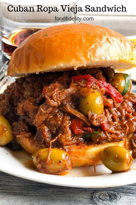 Cuban Ropa Vieja sandwich - tender strands of shredded beef stewed in a rich, flavorful sauce of tomatoes, onions, peppers, olives, garlic & spices. #slowcookerrecipe #tailgatingrecipe #caribbeanfood #stewedbeef #sandwich www.foodfidelity.com Slow Cooker Cuban Sandwiches, Cuban Ropa Vieja Recipe Instant Pot, Shredded Beef Stew, Traditional Cuban Sandwich, Columbia Restaurant Cuban Sandwich, Ropa Vieja Recipe, Cuban Sandwhich, Meatloaf Sandwich, How To Cook Meatloaf