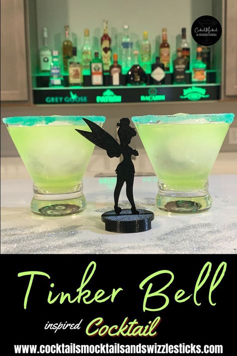 This image shows two green cocktails with a green rim in front of a bar with a Tinerbell Sillouhette in between them and silver glitter scattered around Disney Mixed Drinks, Live Action Peter Pan, Disney Inspired Drinks, Disney Alcoholic Drinks, Bartender 101, Drinks For 21st Birthday, Fall Party Drinks, Classy Cocktail Party, Movie Recipes