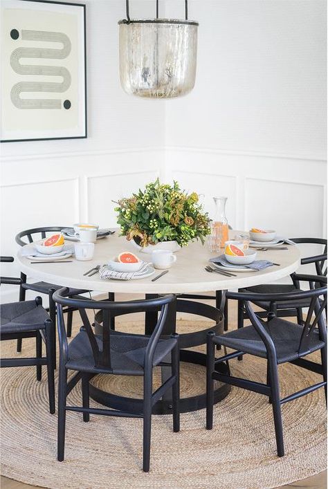 Round wood and iron table feature black wishbone chairs on a round jut rug illuminated with a mercury glass chandelier in a transitional dining room design. Black Wishbone Chair, Mindy Gayer Design, Boho Dining Room, Transitional Dining Room, Transitional Dining, Round Wood Dining Table, Newport Coast, Live Beautifully, Iron Table