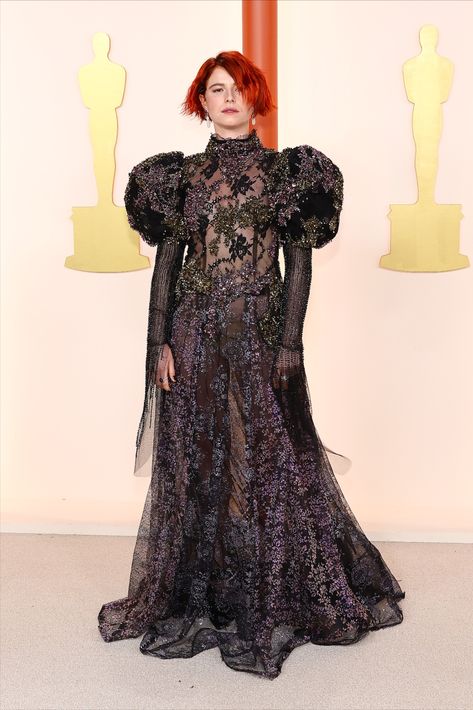 A woman posing for a photo on the Oscars champagne carpet wearing a black floor-length, long-sleeve gown that has puffy sleeves, lots of embellishments and some sheer details. 2023 Oscars, Oscars 2023, Jessie Buckley, Magical Dress, Allison Williams, Winnie Harlow, Brendan Fraser, Halle Bailey, Big Show