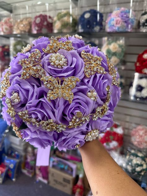 This elegant Quinceañera bouquet is designed to hold and display beautiful silk flowers in a stunning lilac color. Detailed with gold butterflies, this bouquet is sure to complement any Quinceañera gown. Become the center of attention with this beautiful and unique accessory. Quinceanera Bouquet, Wedding Bible, Purple Bouquets, Quinceanera Planning, Ribbon Roses, Lilac Color, Gold Ribbons, Wedding Album, Home Wedding