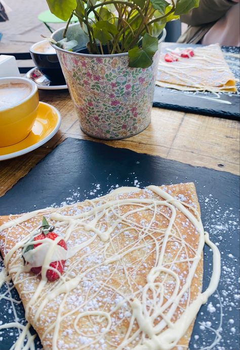 It’s a picture of a crêpe pancake on a black plate with a strawberry and white chocolate stripped over it beside  the  crêpe to the left it has a yellow cup of chai latte Yummy Crepes, Best Crib, Food Tasting, Good Healthy Recipes, Food Coloring, White Chocolate, Small Shop, Pastel Colors, Strawberries