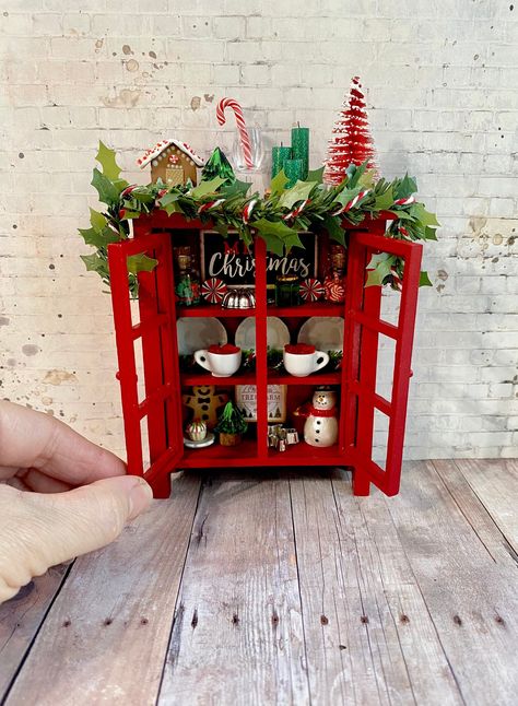 This gorgeous red Christmas cabinet is filled with candies, sweets and Merry decorations and will look smashing in your dollhouse or display. All of the decorations in the cabinet and on top of the cabinet are glued in place. (The faux pine Garland and the items shown sitting on the floor are loose). Decor and sweets are handmade with love. The cabinet measures 5 1/2" high, 4 1/2" wide and 1 1/2" deep. This cupboard will look amazing in any 1:12 scale dollhouse or Christmas display. Thanks for l Dollhouse Holiday, Vintage Christmas Toys, Christmas Miniatures, Christmas Village Sets, Christmas Furniture, Dollhouse Christmas, Mini Doll House, Pine Garland, 1 12 Scale Dollhouse