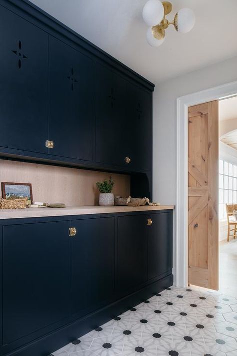 Kitchen features black flat front butlers pantry cabinets with vintage brass latch hardware, gray wash wooden countertops, black and white geometric floor tiles and a reclaimed wood pocket door. Pantry Pocket Door, Dark Blue Cabinets, Floor To Ceiling Storage, Kitchen Island Finishes, Blue Entryway, Transitional Laundry Room, Gray Shaker Cabinets, White Pantry, Latches Hardware