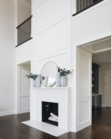 White On White Fireplace, White Fireplace With White Walls, Fireplace Location Ideas, Doorway Beside Fireplace, White Fireplace Dark Floors, Fireplace In Hallway, Open To Below Fireplace, Two Story Double Sided Fireplace, Fireplace Molding To Ceiling