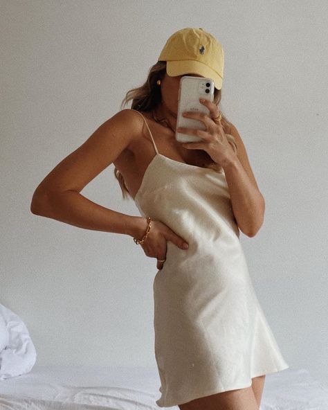 The baseball cap and yellow earrings tame this silk number to give it the simple, sensual look. Yellow Baseball Cap, Ny Cap, Baseball Cap Outfit, Strappy Mules, Rose Details, Ny Outfits, White Silk Dress, Cubs Hat, Cap Outfit