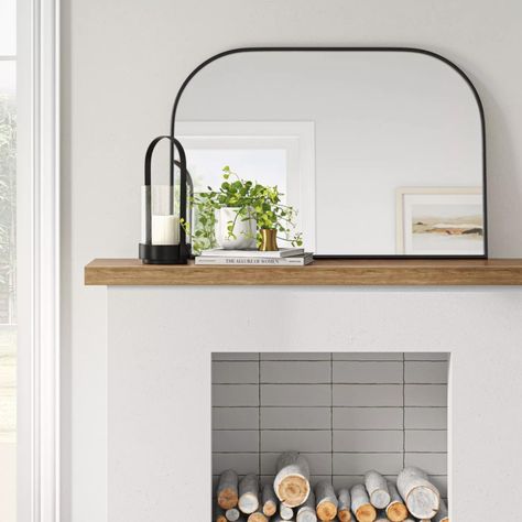 An arched mantle mirror to instantly add depth to your living room. The matte-black frame gives it a modern, minimalist vibe that can be dressed up or down depending on your home style. Arch Mirror On Mantle, Arched Mantle Mirror, Arched Mirror Over Fireplace Mantles, Arched Mirror Mantle, Black Mirror Over Fireplace, Over The Mantle Mirror, Arch Mirror Over Fireplace, Black Mirror On Mantle, Mirror For Mantle