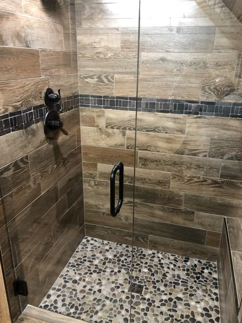 Wood-look Tile Shower with Pebble Floor Grout Colors For Pebble Tile, Rustic Shower Floor Ideas, Pebble Rock Shower Floor, Wood Tile For Bathroom, Wood Tiled Showers, Tile Shower Ideas Rustic, Wood-look Shower Tile Ideas, Wood Look Shower Tile Ideas, Vinyl Tile Shower Walls