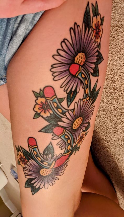 Traditional style tattoo with horseshoes and purple Aster flowers. Andy Northup tattoo Aster Flower Tattoo American Traditional, Traditional Aster Flower Tattoo, Aster Flower Tattoo, Aster Tattoo, Aster Flower Tattoos, Purple Aster, Knee Tattoos, Aster Flowers, Story Tattoo