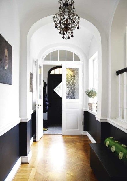 When clients ask about chair rails, I often suggest that they paint everything below it a glossy white so that it becomes more of an architectural element in the room. I also love how the crisp white looks against a really bold color on top.          (This photo is Conan O’Brien’s dining room, … Lambriseringen Gang, Black And White Hallway, White Hallway, Narrow Hallway, Chair Rail, Entry Hall, Entry Way, The Ceiling, Style At Home