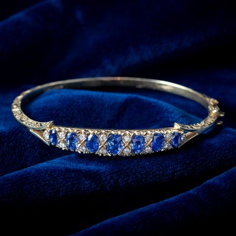 A beautiful vintage sapphire and diamond bangle modelled in 9ct gold with ornate, foliate engraving around the entire band. Seven oval cut sapphires graduate across the front gallery (approx. 3ct total) and have a pleasing cornflower blue hue, complemented by fourteen bright diamonds in between (approx. 0.56ct total). The piece is in excellent condition and complete with London hallmarks within the band, dating the piece to 1989. It’s fitted with a box clasp at the side with a safety catch a... Sapphire Bangle, Edwardian Engagement Ring, Vintage Sapphire, Box Clasp, Diamond Bangle, Memento Mori, Cornflower Blue, Antique Jewellery, Sapphire Diamond