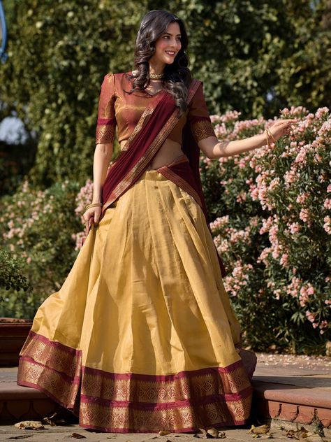 Introducing an exquisite ensemble that embodies the rich heritage of Kanchipuram silk – a cream color Kanchipuram silk lehenga paired with a maroon choli and a matching maroon georgette dupatta. This stunning attire is meticulously crafted to bring out the elegance and sophistication of traditional Indian craftsmanship. The cream lehenga is adorned with intricate zari weaving work, offering a luxurious and opulent appearance that is perfect for grand occasions. The lehenga, tailored to perfectio Telugu Traditional Dress, Cream Kanchipuram Silk Saree, Kerala Saree Blouse Designs Traditional, Trendy Half Saree Designs, Banarasi Lehenga Blouse Design, Kanchi Pattu Lehenga Half Saree, Half Saree Blouse Designs, South Indian Lehenga, Cream Lehenga