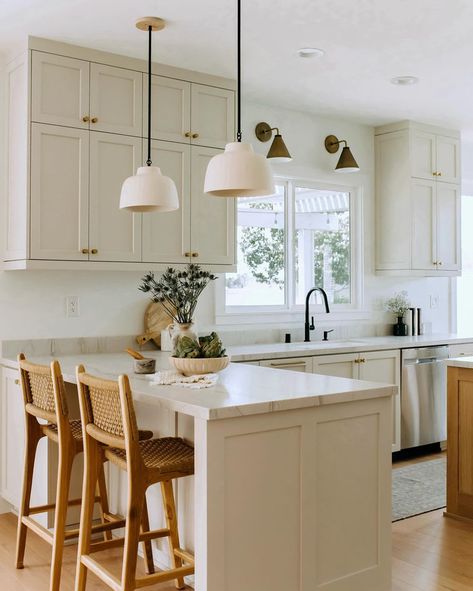 If you have an L-shaped kitchen or a kitchen peninsula, let this kitchen design by @highandtightdesign serve as inspiration for your space. We love the mix and match light fixtures, light neutral kitchen paint color, and woven rattan counter stools. Island In Breakfast Nook, Kitchen Peninsula With Upper Cabinets, Kitchen With Peninsula Seating, L Counter Kitchen, Neutral Kitchen Small, Gallery Kitchen With Peninsula, Peninsula Bar Stools, Small Kitchen Vaulted Ceiling, Bright Apartment Kitchen