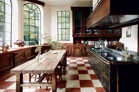 The kitchen of a Belgian château by Axel Vervoordt Walnut Kitchen Dark Countertop, Architectural Digest Wallpaper, Red And Wood Kitchen, Armchair In Kitchen, Wood On Wood Kitchen, Axel Vervoordt Kitchen, Architectural Digest Dining Room, Black And Wood Interior Design, Red Wood Kitchen