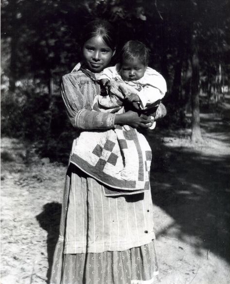 A photograph taken outdoors of a young Choctaw woman in a cotton dress holding a child. Choctaw Clothing, Choctaw Art, Choctaw Tribe, Choctaw Indian, Choctaw Nation, Nichelle Nichols, Aboriginal American, Oklahoma History, American Indian History