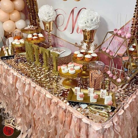 Set up a glimmering dessert table with all things festive. Cover the table with a gold big sequin Payette tablecloth and attach a blush curly willow taffeta skirt to it for a captivating allure. Flaunt white rose balls on gold hammered trumpet vases to impart a dreamy flair. Also, set jars, decorative gold trays, and cake and cupcake stands to glam up your dessert presentation. Gold Dessert Table, Gold And White Cake, Event Decor Ideas, Party Decorations Table, Gold Dessert, Dessert Presentation, Cake And Cupcake Stand, Gold Tray, Dessert Table Decor