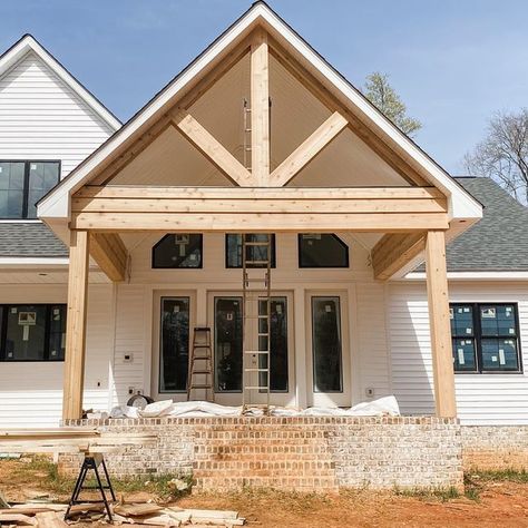 Emily | Couple Acre Wood on Instagram: "🌟 This cedar clad gable and beam detail on our back porch came out STUNNING!! It has almost a mountain resort feel if you ignore the ladders and red mud! I’ll say that the “posts” are cedar cladded onto a pine post, not full cedar, and I love the look. Eventually all the cladding will be stained and the patio doors will be painted black like the windows. Just need to do some power washing and landscaping but this backyard is already jaw dropping!! . . . Cedar Beams Porch, Diy Exterior Door, Porch Beams, Stained Beam, Brick Porch, Diy Exterior, Cedar Posts, Cedar Cladding, Outdoor Structure