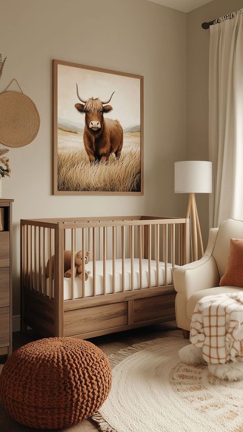 A rustic baby girl nursery with a natural wood crib, a Highland cow wall art, a rust-colored knit pouf, and a beige armchair. The design is completed with soft neutral tones, cozy textiles, and a round cream rug with fringe for a warm farmhouse-inspired atmosphere.