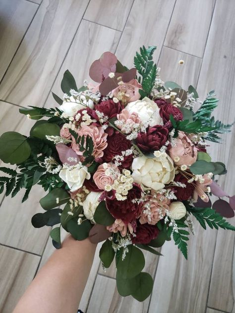 Sola wood flower bohemian style wedding bouquet with dusty rose and burgundy flowers. Greenery is a mixture of artificial and preserved and includes preserved fern, eucalyptus, star flower and german statice. Pictured is the medium 10 inch bridal. Can also be made in smaller and larger sizes. Please see last page for size options. Made to order! Please allow 6-8 weeks for production. Can also add matching bridesmaid bouquets, corsages, boutonnieres, cake flowers, and flower crowns per request. C Wedding Flowers Maroon, Burgundy Wedding Bouquet Bridesmaid, Cabernet Bouquet, Burgundy Eucalyptus Wedding, Cinnamon Rose Wedding Bouquet, Maroon Flower Bouquet, Emerald And Dusty Rose Wedding, Wine And Dusty Rose Wedding, Cabernet Wedding Colors Flowers