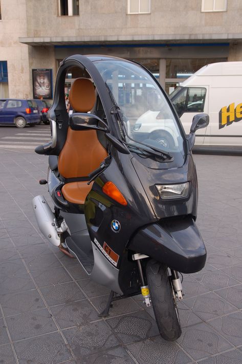 The BMW C1 was an enclosed scooter manufactured by Bertone for BMW.[1] Compared to a conventional scooter, the C1 offered extra safety features and protection from the elements. The rider would sit in a car-type seat and adopt a feet-forward posture.[2] Introduced in 2000, it was available throughout Europe, but sales were disappointing and the C1 was discontinued in 2002. In 2009 the C1-E electric version was presented as a concept. Bmw C1, Peacock Pictures, Tricycle Bike, Fresh Cake, Bmw Cafe Racer, Bmw Motorcycles, A Concept, Sidecar, Tricycle