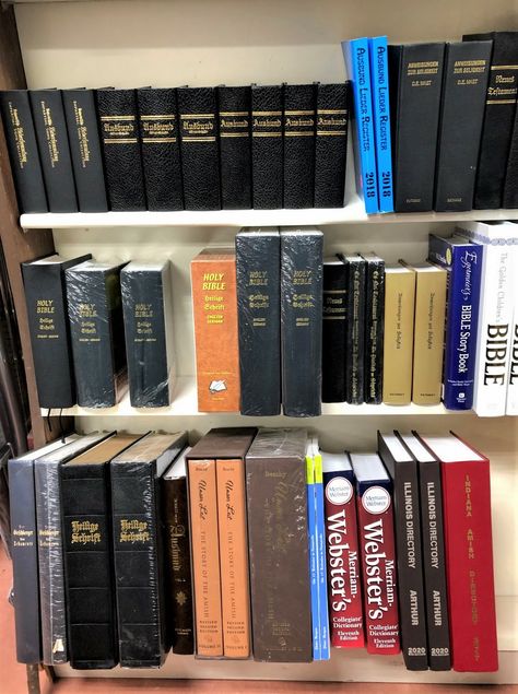 This book display shows the basics that every Amish home might have.  On the top shelf, copies of the “Ausbund,” the Sunday morning hymnal, and a lesser-known hymnal that some Amish groups use.  Both are hundreds of years old, and written in Old German.  On the middle shelf, English/Old German parallel Bibles.  On the bottom shelf, Old German Bibles, among other useful things. Bible Shelf Ideas, Old Books On Shelf, Books Of The Bible Wall, Books Of The Bible Bookshelf, Bible Coffee Table Books, Bible Books Classification, Bible Story Book, Amish House, Plain People