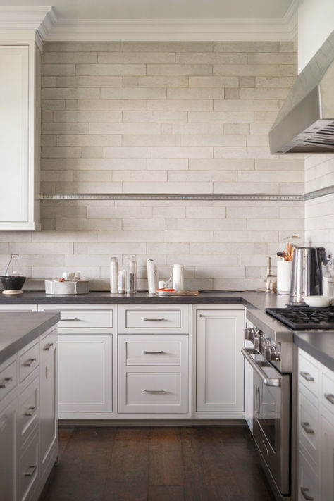 A kitchen with white cabinets, a long neutral-tile backsplash, and dark countertops Neutral Kitchen Tiles, White Cabinets Dark Countertops, Neutral Kitchen Backsplash, Neutral Backsplash Kitchen, Kitchen With White Cabinets, Backsplash Kitchen Ideas, Backsplash With Dark Cabinets, Neutral Backsplash, Neutral Tile