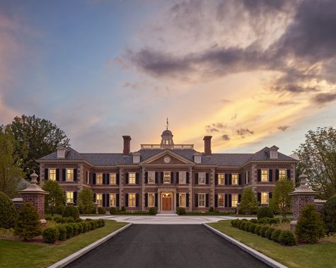 Thoughtful consideration was taken in the selection of the brick’s blend of red tones, which are complemented by the soft warm hues of the sandstone accents on this new Georgian style estate. #brickpiers #slateroof #limestonequoins #redbrickhouse #cupola #pedimentedentry #drivecourt #symmetricalarchitecture #georgianarchitecture #traditionaldesign #classicalarchitecture #sunset #newenglandestate Brick House Mansion, Red Brick Mansion Exterior, Georgian Style Architecture, Red Brick Mansion, Bloxburg Colonial Mansion, Brick Mansion Exterior, Colonial Mansion Exterior, Georgian Style Homes Exterior, Brick Georgian House