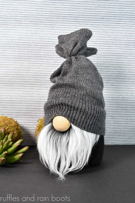 Vertical image of a black sock gnome with faux fur beard in gray with a sweater sleeve hat in gray. Ruffles And Rain Boots Gnome, Adult Gnome Hat Pattern, Diy Large Gnomes How To Make, How To Make A Gnome Hat, Gnome Hat Patterns, Diy Gnome Hat, Gnome Hats Diy Free Pattern, Free Gnome Patterns, Gnome Hat Pattern