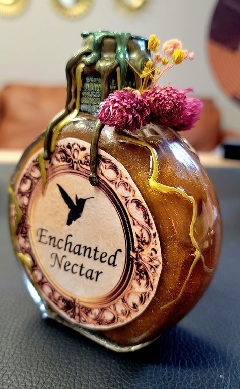 Step into the mystical realm with our Enchanted Nectar Potion Bottle - a glass-crafted masterpiece that transcends the ordinary. Meticulously handcrafted with an unwavering attention to detail, this bottle is not just an accessory; it's a bewitching fusion of witchy charm, boho elegance, and earthy allure designed to elevate your home decor. The Enchanted Nectar Potion Bottle beckons with its entrancing design, featuring an exquisite blend of botanical and floral elements. Crafted with a touch of magic, this bottle captures the essence of an otherworldly elixir, bringing a sense of enchantment to any space. Designed for those who embrace the unconventional and appreciate the ethereal, this potion bottle is a unique statement piece. With crystals carefully embedded within, it creates a mesm Weird Bottles, Truth Potion, Witchy Potion Bottles, Witch Potions Aesthetic, Vintage Glass Bottles, Witch Potions, Magic Potion, Witch Potion, Witch Bottles