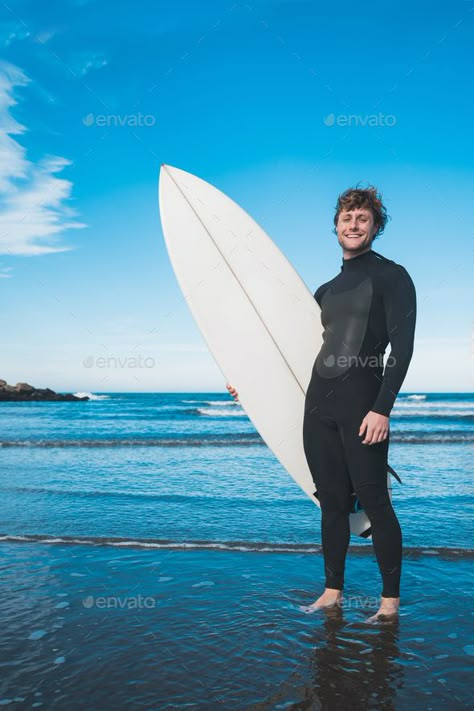 Surfer standing in the ocean with his surfboard. by megostudio. Young surfer standing in the ocean with his surfboard in a black surfing suit. Sport and water sport concept. #Sponsored #megostudio, #Young, #surfer, #surfboard Posing With Surfboard, Surfing Poses Reference, Surfer Holding Surfboard, Man With Surfboard, Holding Surfboard Pose, Surfer Pose Reference, Surfer Reference, Beach Reference Pose, Surfing Pose Reference