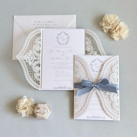 This elegant dusty blue wedding invitation features a vintage custom design, complete with lace and a handmade touch. Personalize your celebration with a botanical monogram crest on this exquisite custom wedding card, perfect for your special day. Invitations printed on White metallic card stock and mounted to the inside White laser cut folder with Dusty Blue ribbon.  Envelopes in White metallic.  I N C L U D E S - 5" X 7.25" Lace Laser Cut Folder with Satin bow - Printed Invitation mounted to t Nantucket Beach Wedding, 2025 Wedding Invitations, White Blue And Gold Wedding, Cornflower Blue Wedding Invitations, Blue Invitations Wedding, Diy Wedding Invitations Handmade, Vintage Glam Wedding Invitations, Wedding Invitations Cricut, Blue And White Wedding Invitations