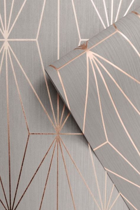 This stylish Kayla Geometric Wallpaper would make a great statement in most rooms of your home. The design features a geometric pattern of elongated triangles with a contemporary metallic rose gold finish that catches and reflects the light. This is set on a soft grey matte background with a subtle lined texture. Easy to apply, this high quality wallpaper would look great when used to create a feature wall or to decorate an entire room. Wallpaper Bedroom Feature Wall, Geo Wallpaper, Feature Wall Bedroom, Wallpaper Inspiration, Building Remodeling, Metallic Wallpaper, Drinks Cabinet, Grey Roses, Gold Wallpaper