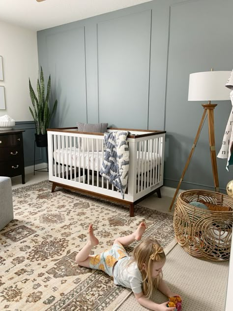 The beautiful trim work/accent wall is a focal point in this gender neutral nursery! Gender Neutral Nursery With Accent Wall, Nursery Room Accent Wall Ideas, Gender Neutral Accent Wall Nursery, Nursery Wall Trim, Accent Wall Baby Boy Nursery, Teal Accent Wall Nursery, Nursery With Grey Walls, Boy Nursery Wallpaper Accent Wall, Neutral Nursery With Blue Accents