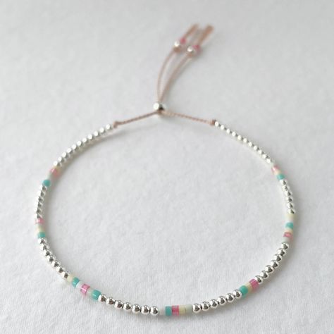 The Reef bracelet captures the delicate beauty and colours of the underwater world with sterling silver beads and turquoise, pink, lemon, mint and white glass beads is strung on a pale pink silk cord and has a silver sliding clasp to adjust to your size. Displayed in one of our pretty gift boxes, so fantastic as a present for a friend or to yourself! Details -Pale pink silk cord -Sterling silver sliding bead and 2mm beads -Japanese glass beads in pink, turquoise, mint, lemon and white -Extends to maximum of 9in to fit over the wrist with a minimum size of 6in Please contact me for a custom size Handmade Pink Bracelets For Beach, Casual Pink Beaded Bracelets With Adjustable Cord, Pink Delicate Adjustable Bracelet, Pink Hand-strung Beaded Bracelets For Beach, Adjustable Pink Nylon Cord Bracelet, 2mm Beads, Silk Bracelet, Pink Lemon, The Reef