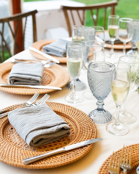 Rattan lampshades, a hint of ‘something blue’, greenery, and our Willow chairs are a stunning combination under our Sperry Tent! Dusty blue goblets, light blue napkins, and rattan chargers tied together the wedding theme for Nora + CJ’s spring wedding at Willowdale Estate. This elegant tent inspiration takes you from day to night with a warm glow from the tent lighting and colorful uplights illuminating the dance floor. Nora & CJ’s Wedding Team: Venue @willowdaleestate Photography @melanie... Blue And Rattan Wedding, Woven Chargers Table Settings Wedding, Rattan Chargers Table Setting Wedding, Wedding Rattan, Rattan Wedding, Rattan Charger Plate, Blue Goblets, Willowdale Estate, Sperry Tent