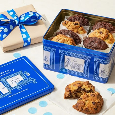 Elevate the joy of Levain cookies with our signature tin — a delightful gift that combines 8 iconic cookies and a lasting memento in our classic blue hue. An homage to our roots, the signature tin features our West 74th Street bakery, where our founders Connie & Pam first made our iconic cookie back in 1995. The charming blue tin holds 8 cookies packed in beautiful cellophane bags with hand-tied blue ribbons. The tin helps to keep cookies fresh on the counter and serves as a sweet memento long a Artisan Cookies Packaging, Cookies Box Design, Tin Packaging, Levain Cookies Packaging, Luxury Food Packaging, Cookie Package, Premium Cookies Packaging, Levain Cookie Flavors, Cookie Tin Packaging