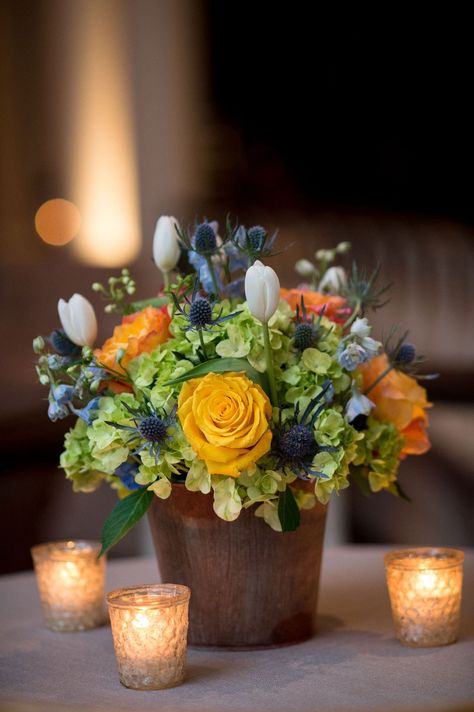 More colorful centerpieces at lounge areas showcased light green hydrangeas, yellow and orange roses, white tulips, and blue thistles. Fall Rehearsal Dinner Decorations Centerpieces, Hydrangea Orange, Dinner Southern, Rehearsal Dinner Centerpieces, Fall Rehearsal Dinners, Wedding Rehearsal Dinner Decorations, Rehearsal Dinner Planning, Fall Floral Centerpieces, Dinner Centerpieces